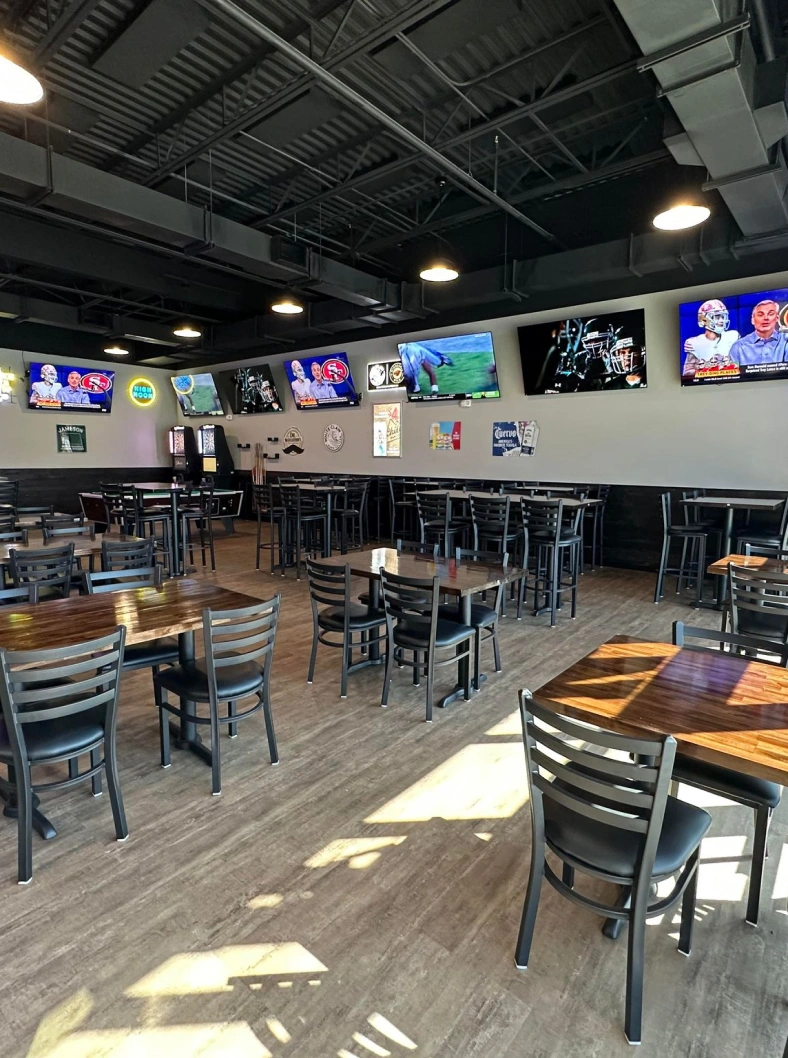 a room with tables and chairs and tvs on the wall.